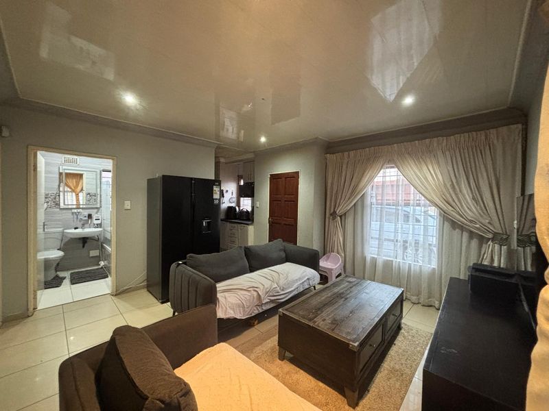 Open-plan living area featuring glossy ceilings, tiled floors, and direct access to an adjacent bathroom and kitchen space.