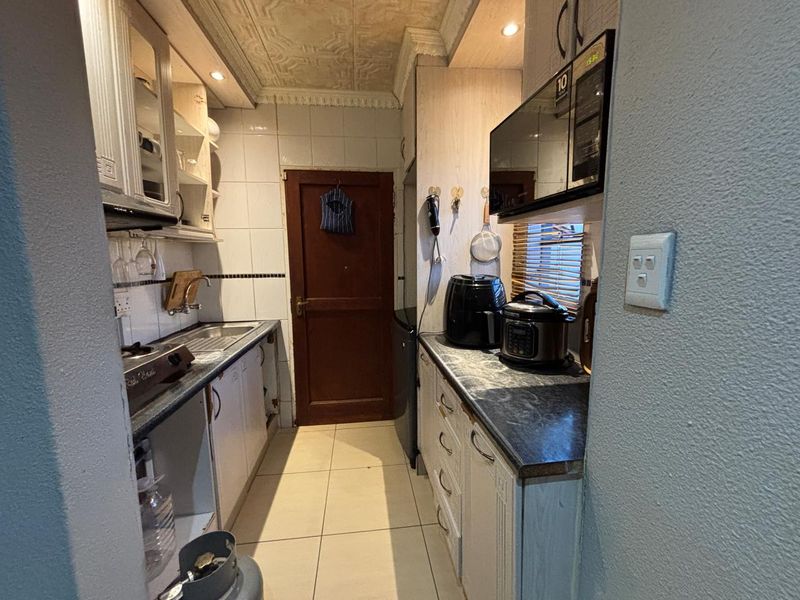 Compact kitchen featuring built-in cabinetry, tiled backsplash, and tiled flooring. The space requires cosmetic updates to modernize the finishes and improve overall functionality.