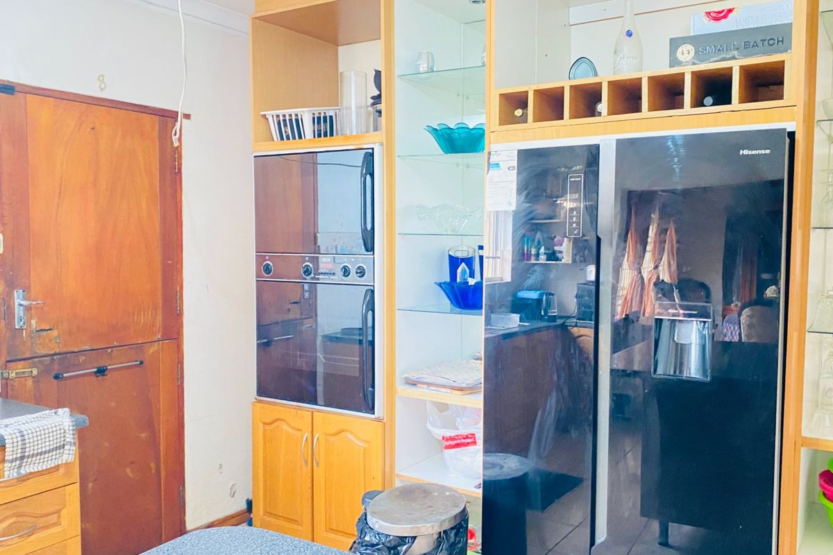 A kitchen area featuring built-in cabinetry, an integrated oven, and dedicated wine storage, showing signs of wear and dated finishes.