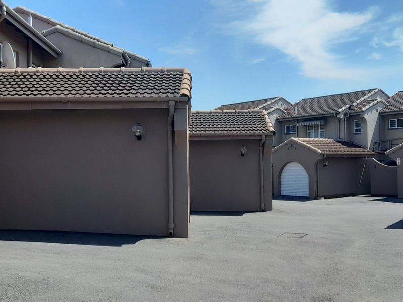 A view of the townhouse complex driveway featuring multiple garage entrances and well-maintained exterior building finishes.