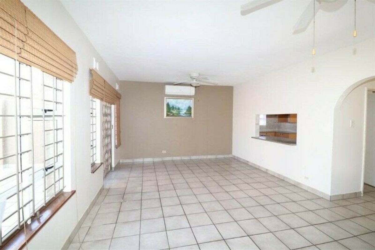 Spacious, tiled living area featuring a ceiling fan, split-system air conditioning, and a convenient serving hatch connecting to the kitchen.
