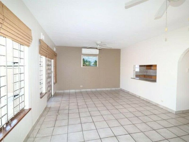 Spacious, tiled living area featuring a ceiling fan, split-system air conditioning, and a convenient serving hatch connecting to the kitchen.