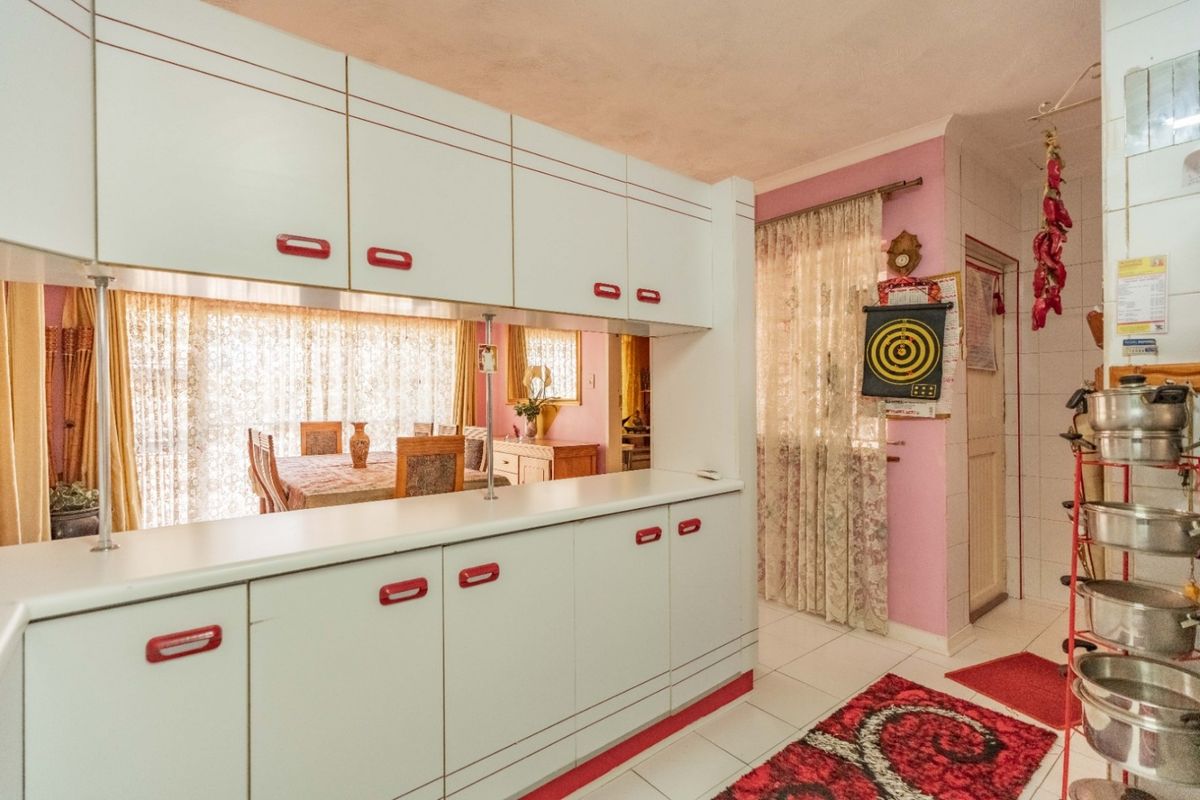A dated kitchen area featuring built-in cabinetry and a pass-through window connecting to the adjacent dining space.