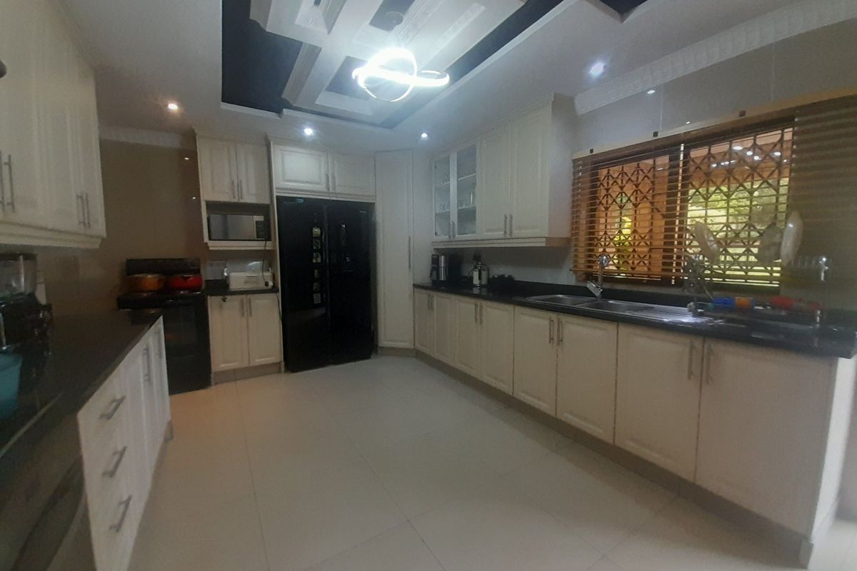 Spacious kitchen featuring cream-colored cabinetry, dark granite countertops, a double sink, and a modern drop ceiling with recessed lighting.