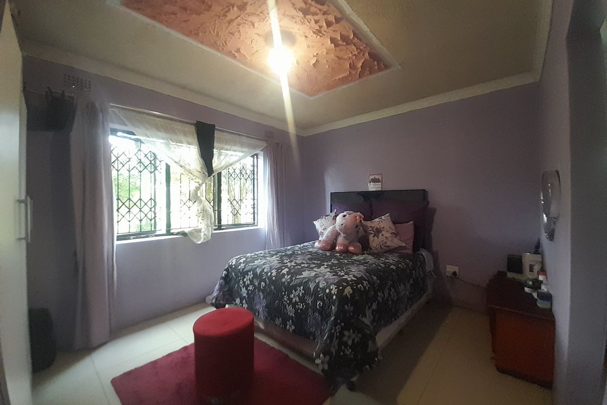 A bedroom featuring tiled flooring, security bars on the window, and a textured ceiling detail.