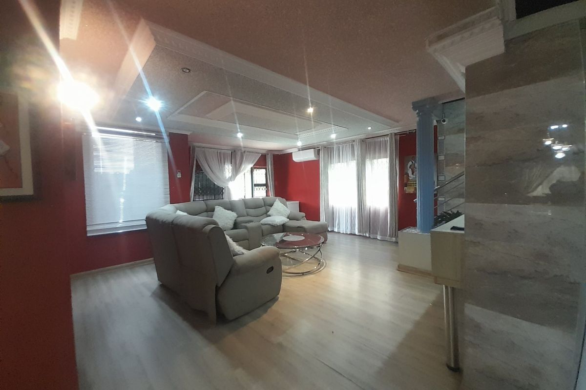 Spacious living room featuring laminate flooring, recessed ceiling lighting, decorative molding, and a wall-mounted air conditioning unit.