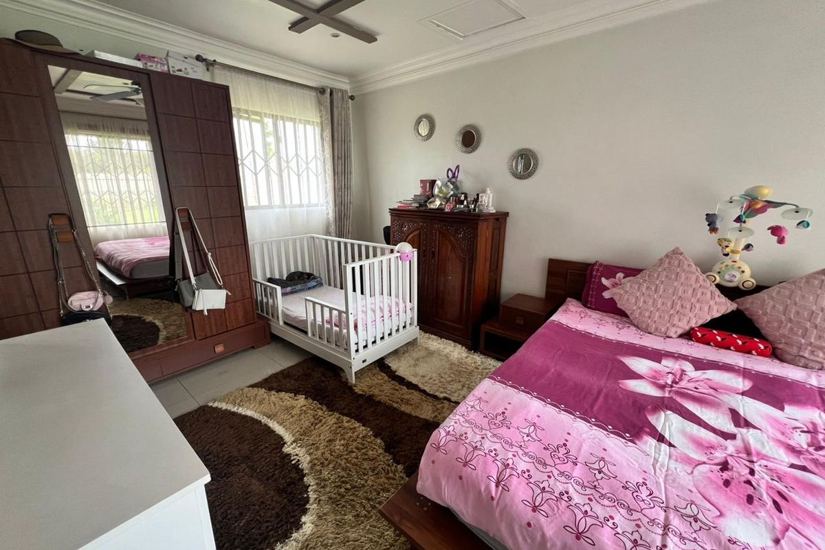 A spacious bedroom featuring tiled flooring, crown molding, a ceiling fan, and security bars on the windows.