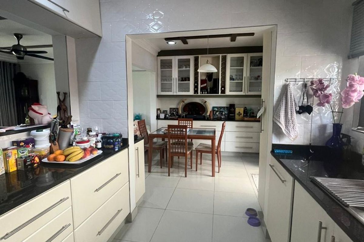 A functional kitchen featuring built-in cabinetry, granite countertops, and tiled flooring, with an open-plan layout leading into the dining area.