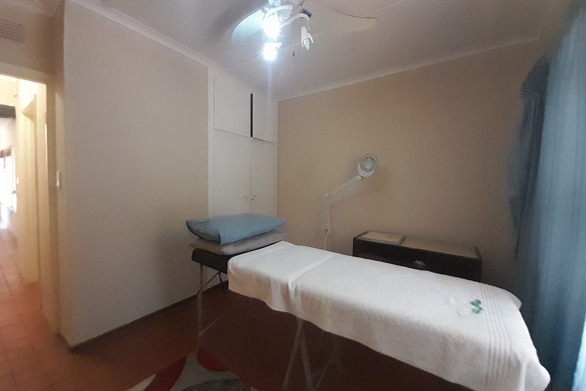 A functional bedroom space featuring a built-in cupboard and ceiling fan, suitable for use as a guest room or home office.