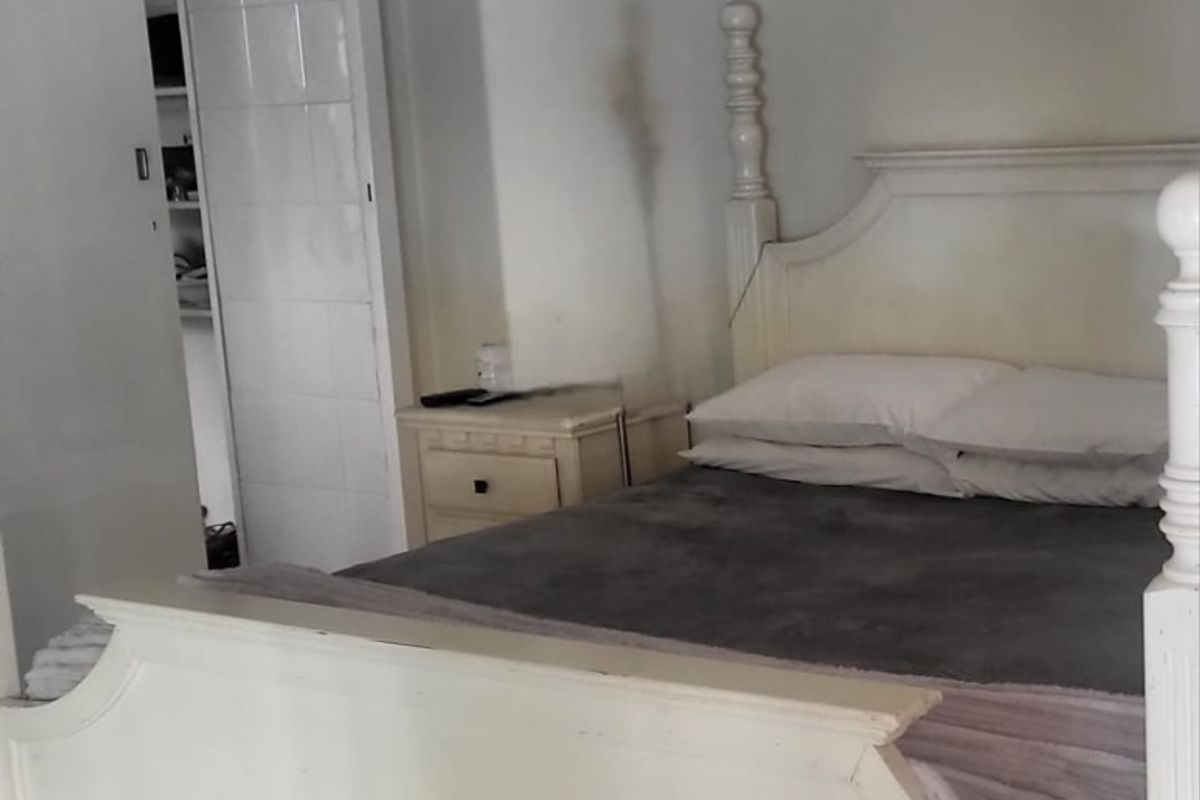 A bedroom featuring a built-in sliding door wardrobe and cove cornice, showing signs of wall staining and surface discoloration.