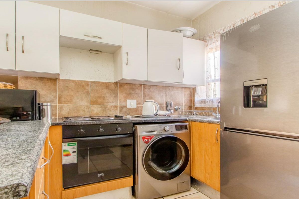 A functional kitchen featuring built-in cabinetry, tiled backsplash, laminate countertops, and integrated oven and hob.
