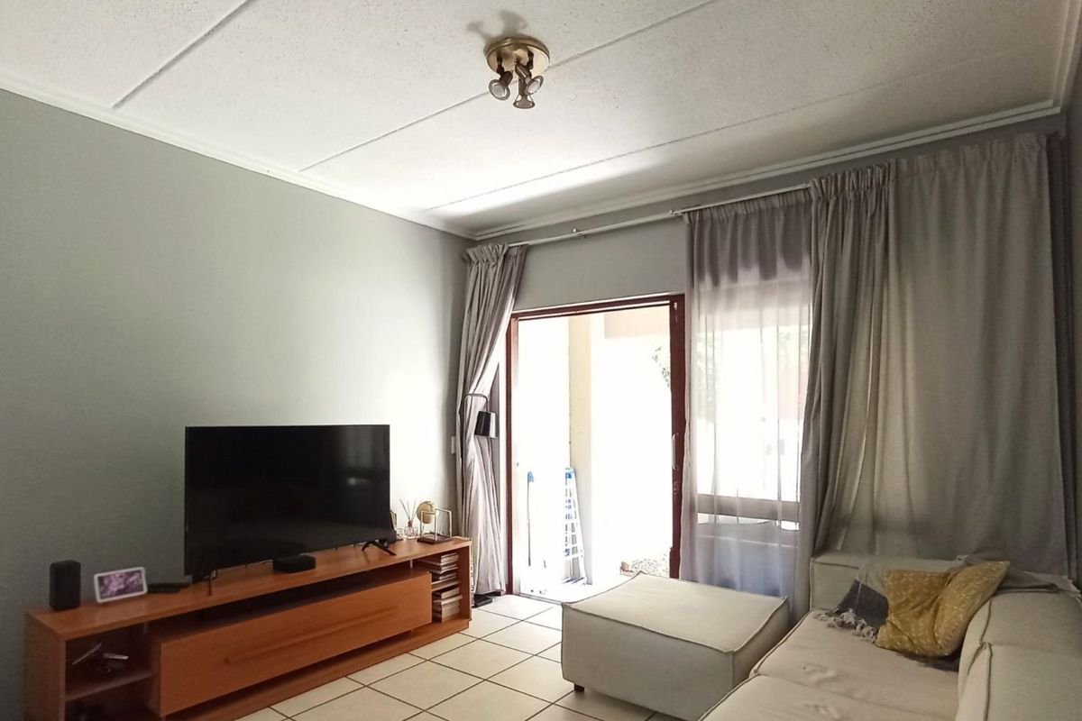 A living room featuring tiled flooring and a sliding glass door providing access to an outdoor area.