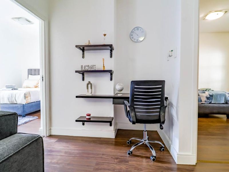 A compact home office nook featuring built-in wall shelving and laminate flooring, situated between two bedroom entryways.