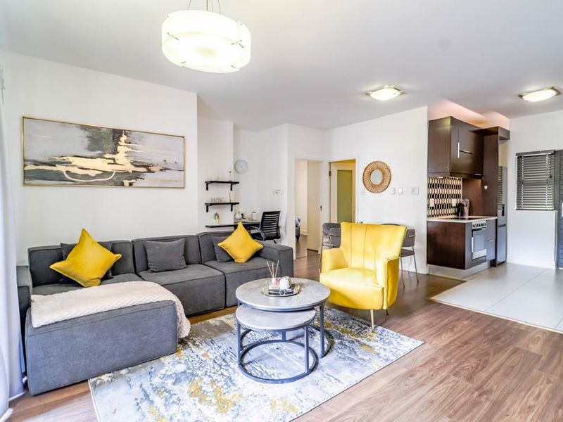 Open-plan living area featuring a modern kitchen with built-in appliances, laminate flooring, and a bright, well-maintained interior layout.