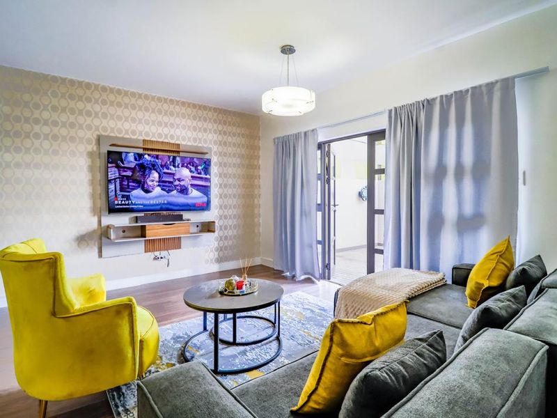 A well-maintained living room featuring laminate flooring, decorative wallpaper, and a sliding glass door providing access to an outdoor area.