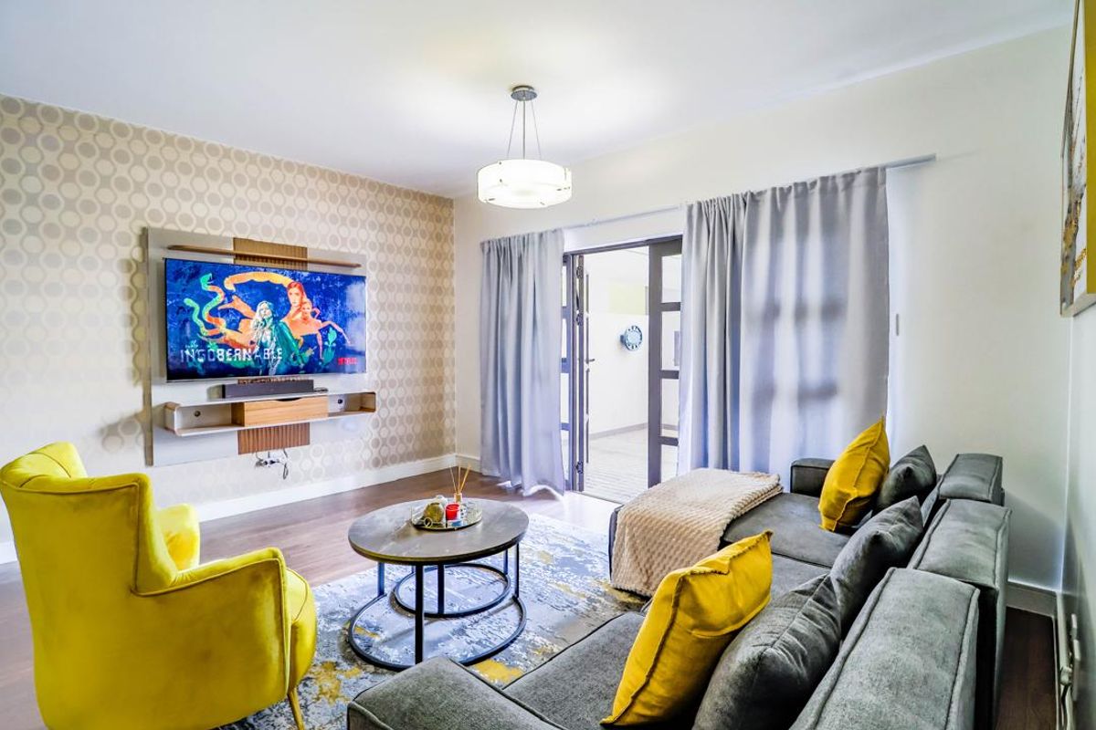 A well-maintained living room featuring a built-in media console, patterned accent wall, laminate flooring, and direct access to an outdoor area via sliding doors.