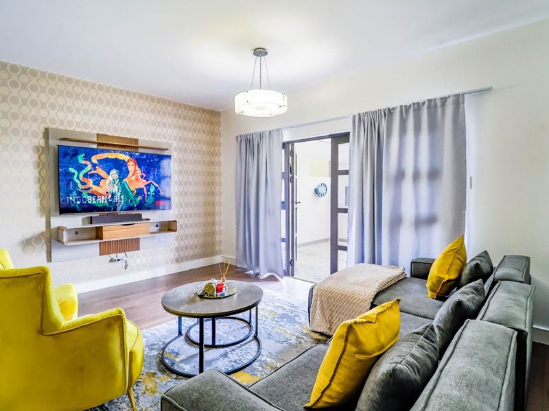 A well-maintained living room featuring a built-in media console, patterned accent wall, laminate flooring, and direct access to an outdoor area via sliding doors.