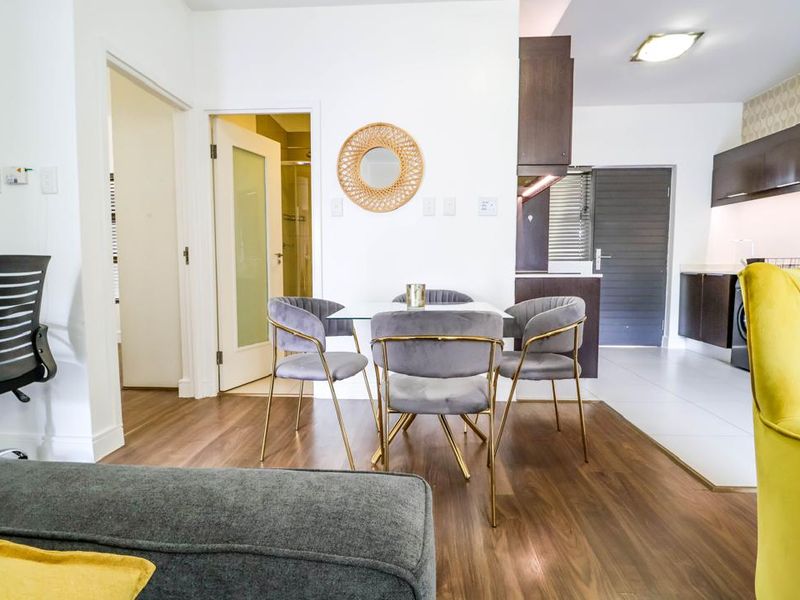 Open-plan living and kitchen area featuring modern laminate flooring, tiled kitchen zone, and contemporary dark cabinetry with integrated lighting.