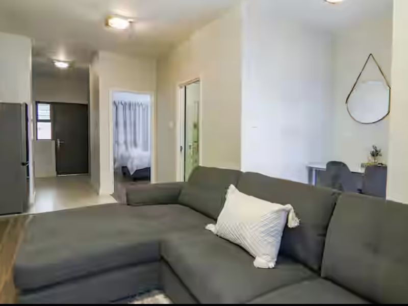 Open plan living area featuring laminate flooring and neutral walls, providing a functional layout with direct access to adjacent rooms.