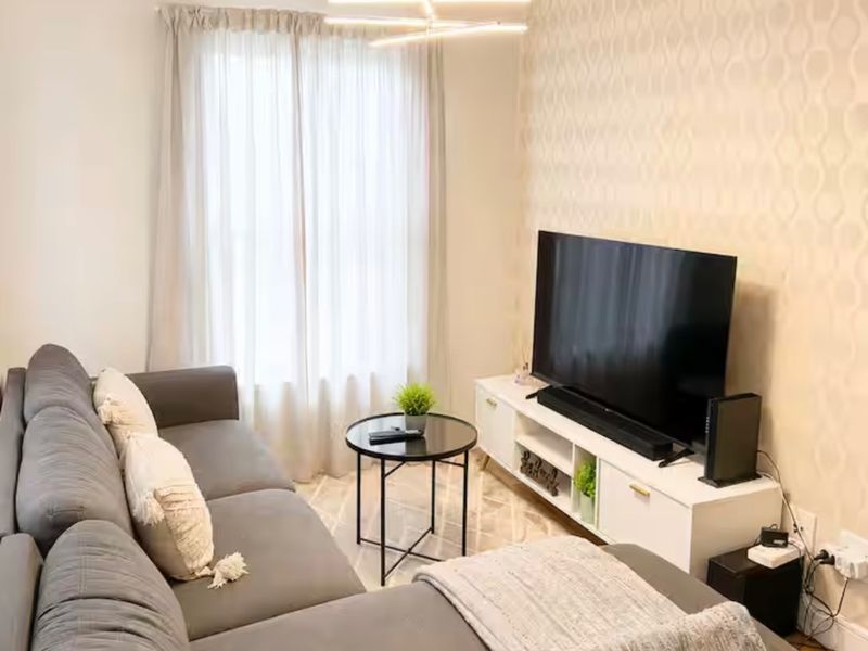 A cozy living room featuring a modern pendant light fixture and a decorative patterned accent wall.