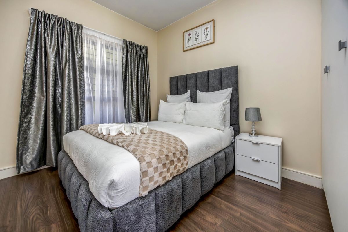 A well-maintained bedroom featuring dark laminate flooring and a built-in wardrobe, offering a clean and comfortable living space.