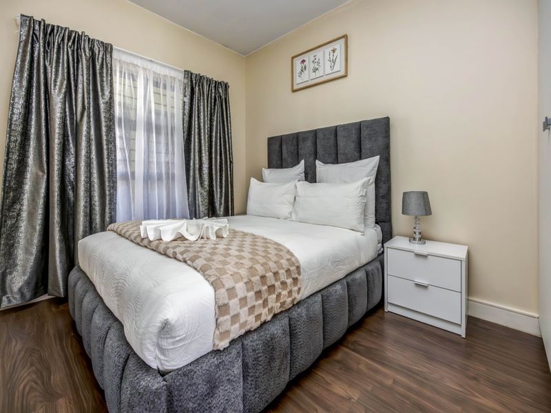 A well-maintained bedroom featuring dark laminate flooring and a built-in wardrobe, offering a clean and comfortable living space.