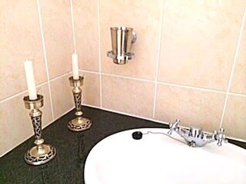 Close-up view of a bathroom vanity featuring a granite countertop, inset basin, chrome mixer tap, and wall-mounted accessories.