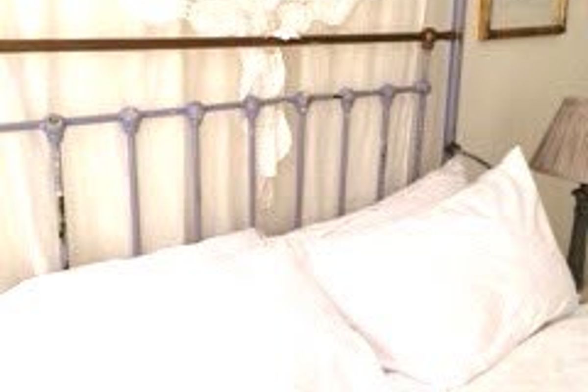 A close-up view of a bedroom space featuring a metal bed frame and window treatments.