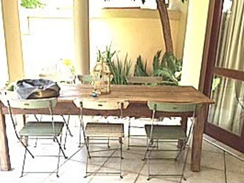 A covered patio area featuring tiled flooring, structural columns, and direct access to the interior through a timber-framed glass door.