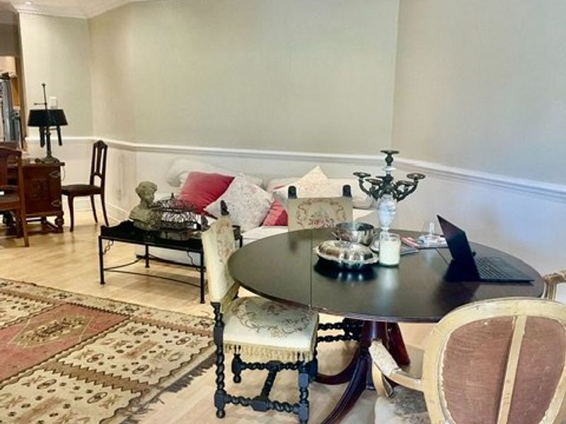 A well-maintained living area featuring light laminate flooring, decorative crown molding, and classic chair rail detailing, providing a bright and neutral foundation.