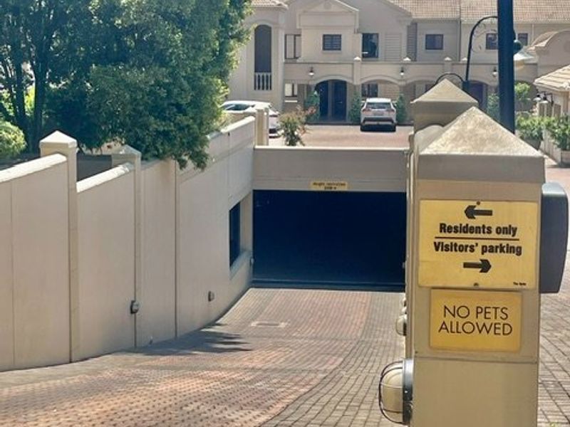 Entrance to the apartment complex featuring a paved driveway leading to an underground parking area with clear signage.