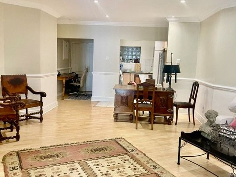 Spacious open-plan living area featuring light laminate flooring, crown molding, and chair rail detailing, with recessed downlighting throughout.