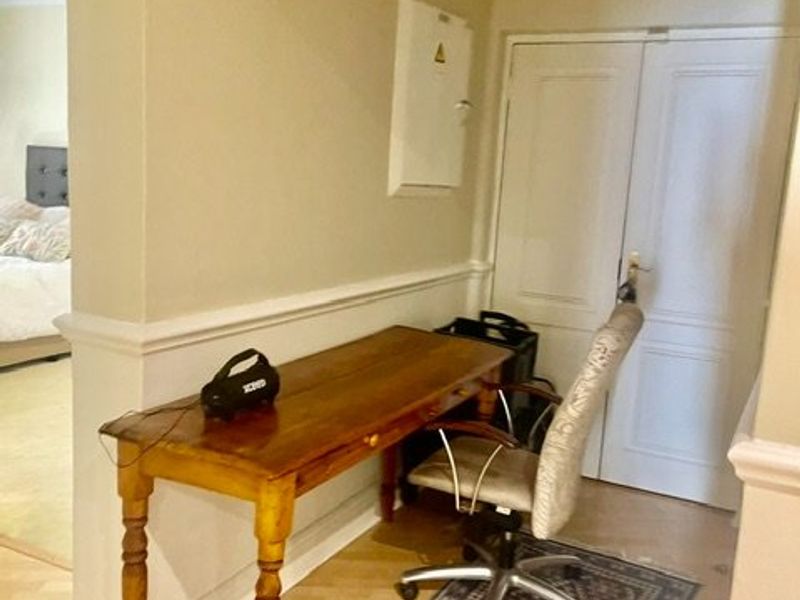 A functional hallway area featuring laminate flooring, wainscoting, and double doors, providing access to adjacent living spaces.