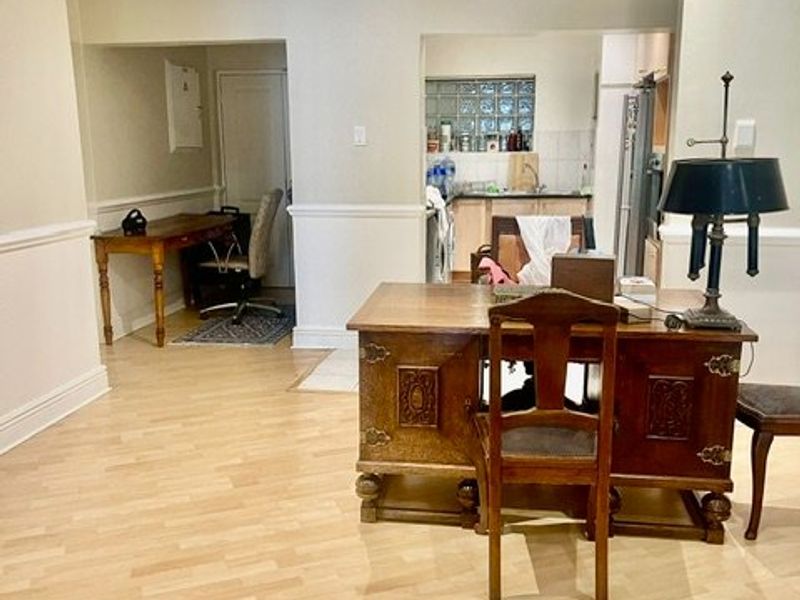 Open plan living area featuring laminate flooring, crown molding, and chair rail detailing, with a view into the adjacent kitchen area.
