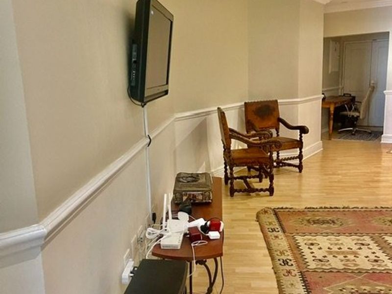 A living room area featuring crown molding, chair rail detailing, and light-toned laminate flooring, providing a neutral foundation for interior design.
