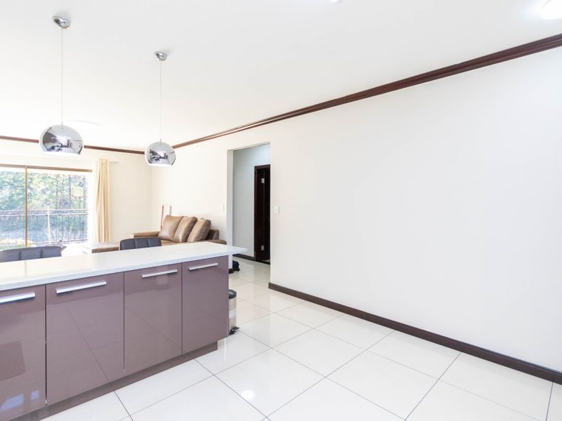 Modern open-plan living area featuring a sleek kitchen island with quartz countertops, glossy cabinetry, and polished porcelain floor tiles throughout.