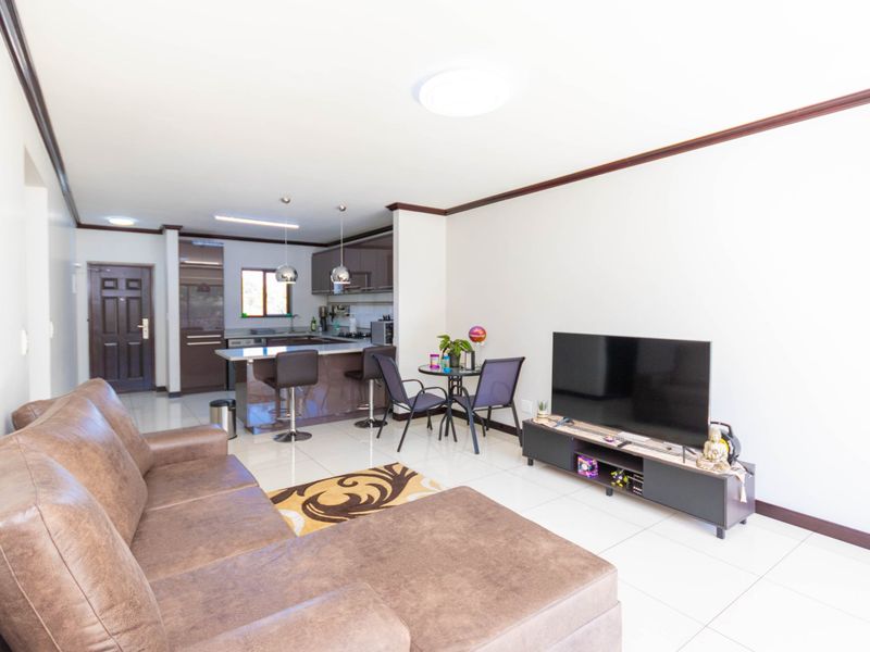 Open plan living area featuring a modern kitchen with island, tiled flooring, and neutral wall finishes, creating a functional and cohesive living space.