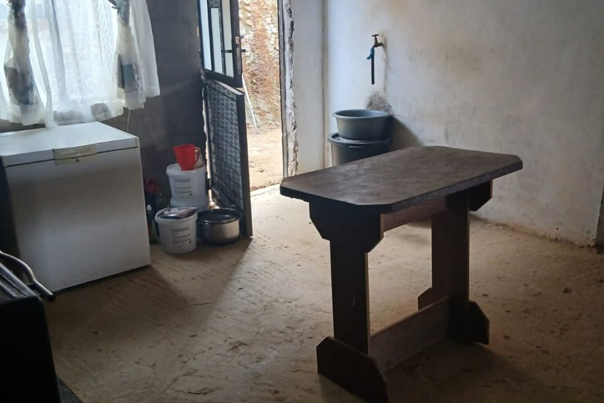 A basic, unfinished utility space featuring exposed earth flooring, raw wall finishes, and a simple wall-mounted water tap.