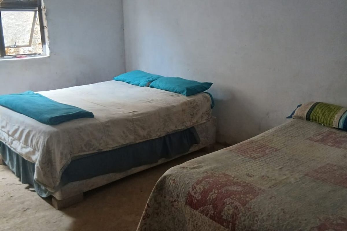 A bedroom featuring basic finishes, exposed ceiling beams, and unfinished flooring, requiring significant renovation to improve the overall condition and aesthetic appeal.