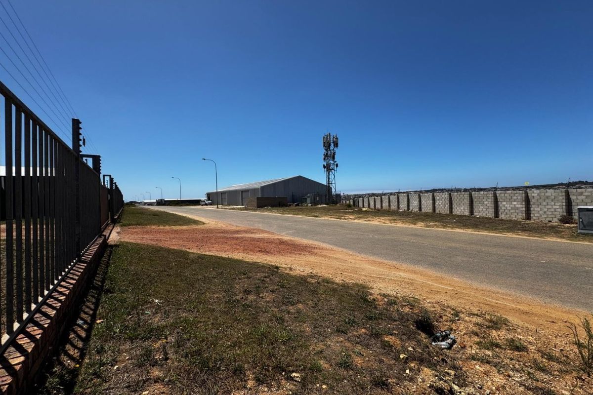A view of the paved street frontage featuring a perimeter wall with electric fencing and a nearby telecommunications tower.