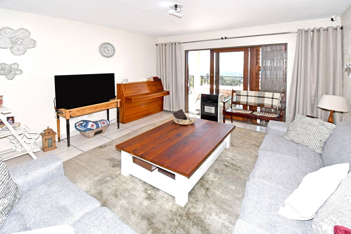 A comfortable living room featuring tiled flooring and a large sliding glass door that provides access to the outdoor patio area.