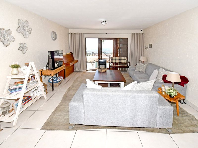 Spacious living room featuring neutral tiled flooring and a sliding glass door providing access to an outdoor balcony area.