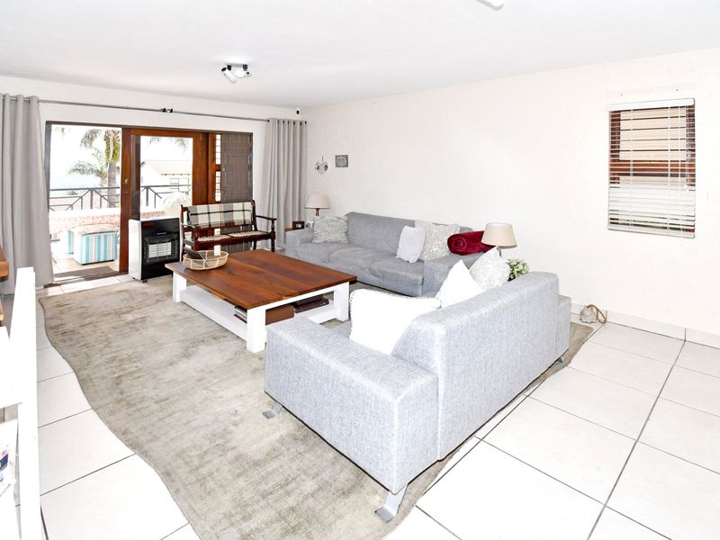 A bright living room featuring tiled flooring, a large sliding glass door leading to an outdoor area, and neutral wall finishes.