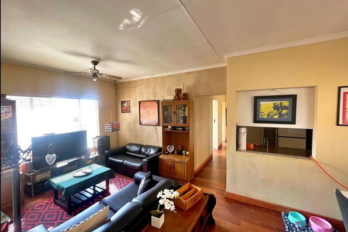 A living room featuring hardwood flooring, a ceiling fan, and a convenient pass-through window connecting to the kitchen area.