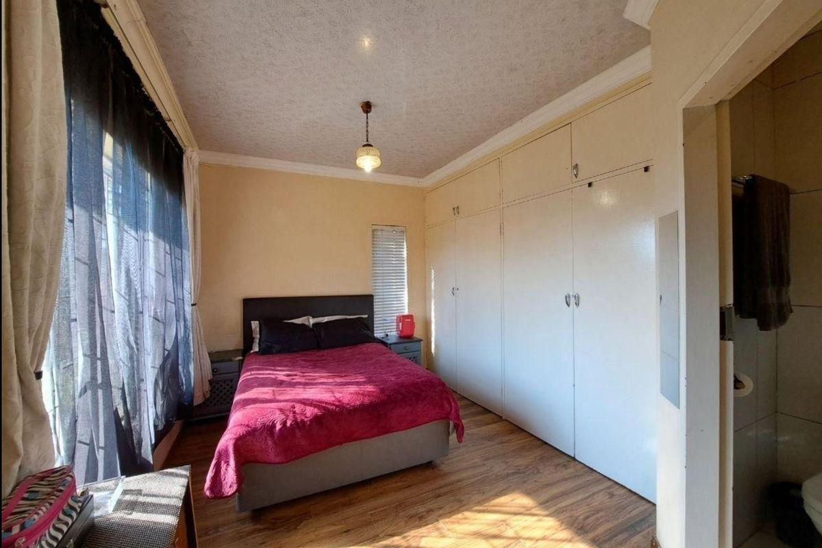 A functional bedroom featuring laminate flooring, built-in cupboards, and direct access to an en-suite bathroom.