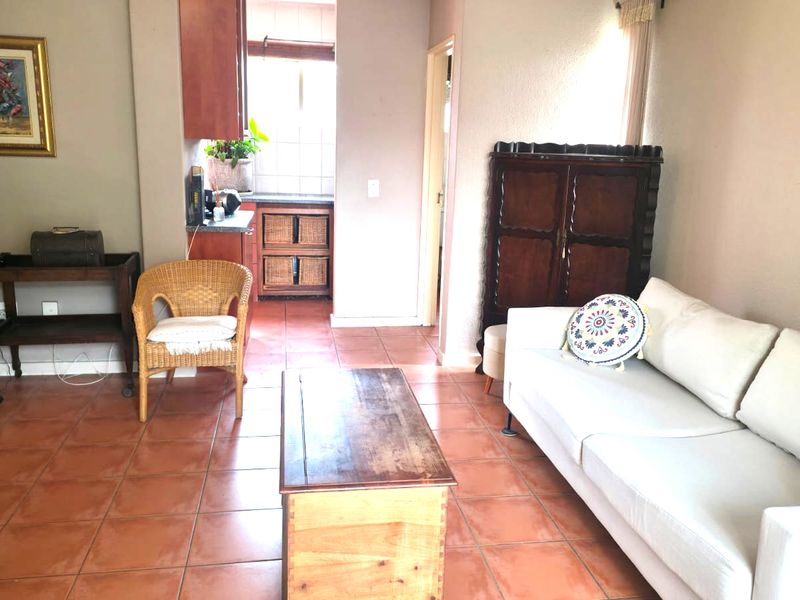 Open plan living area featuring terracotta floor tiles and a compact kitchen space with built-in cabinetry.