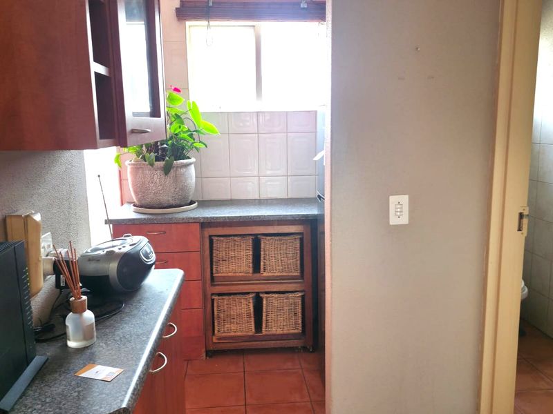 A functional kitchen area featuring laminate countertops, tiled backsplash, and built-in cabinetry, with an adjacent bathroom visible through the doorway.