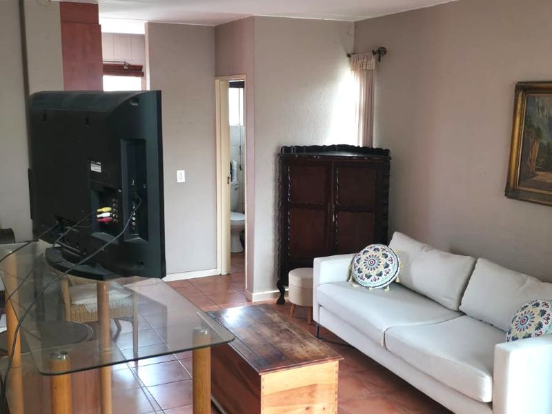 A living room featuring ceramic floor tiles, neutral wall finishes, and access to an adjacent bathroom.