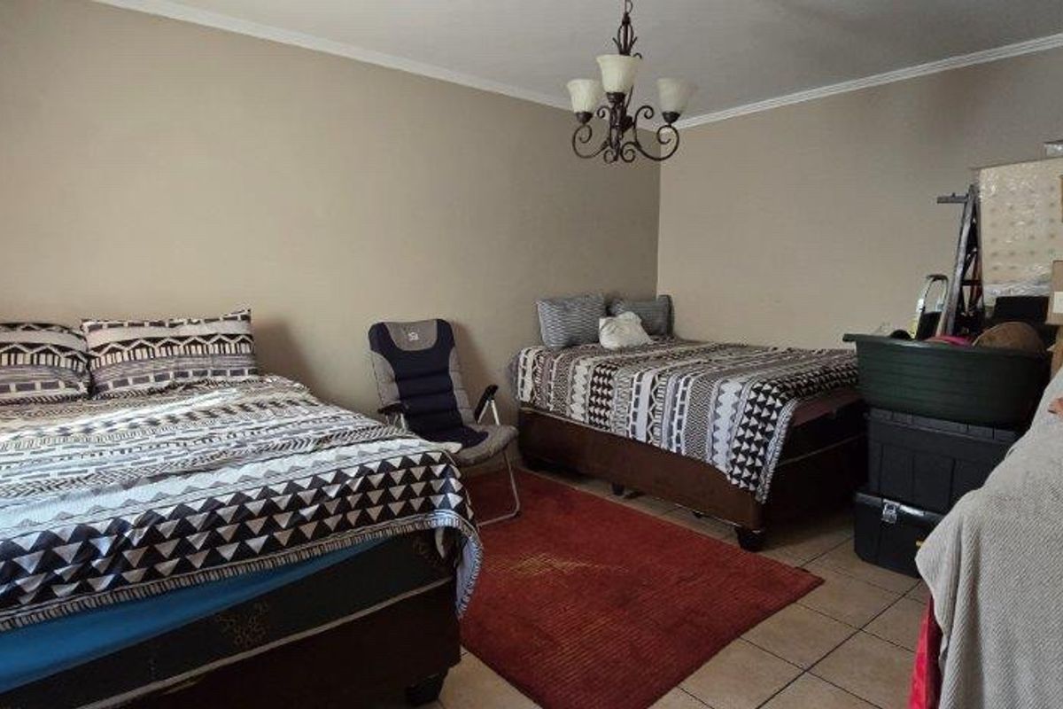 A bedroom featuring tiled flooring and a central ceiling light fixture, providing a functional space for sleeping arrangements.