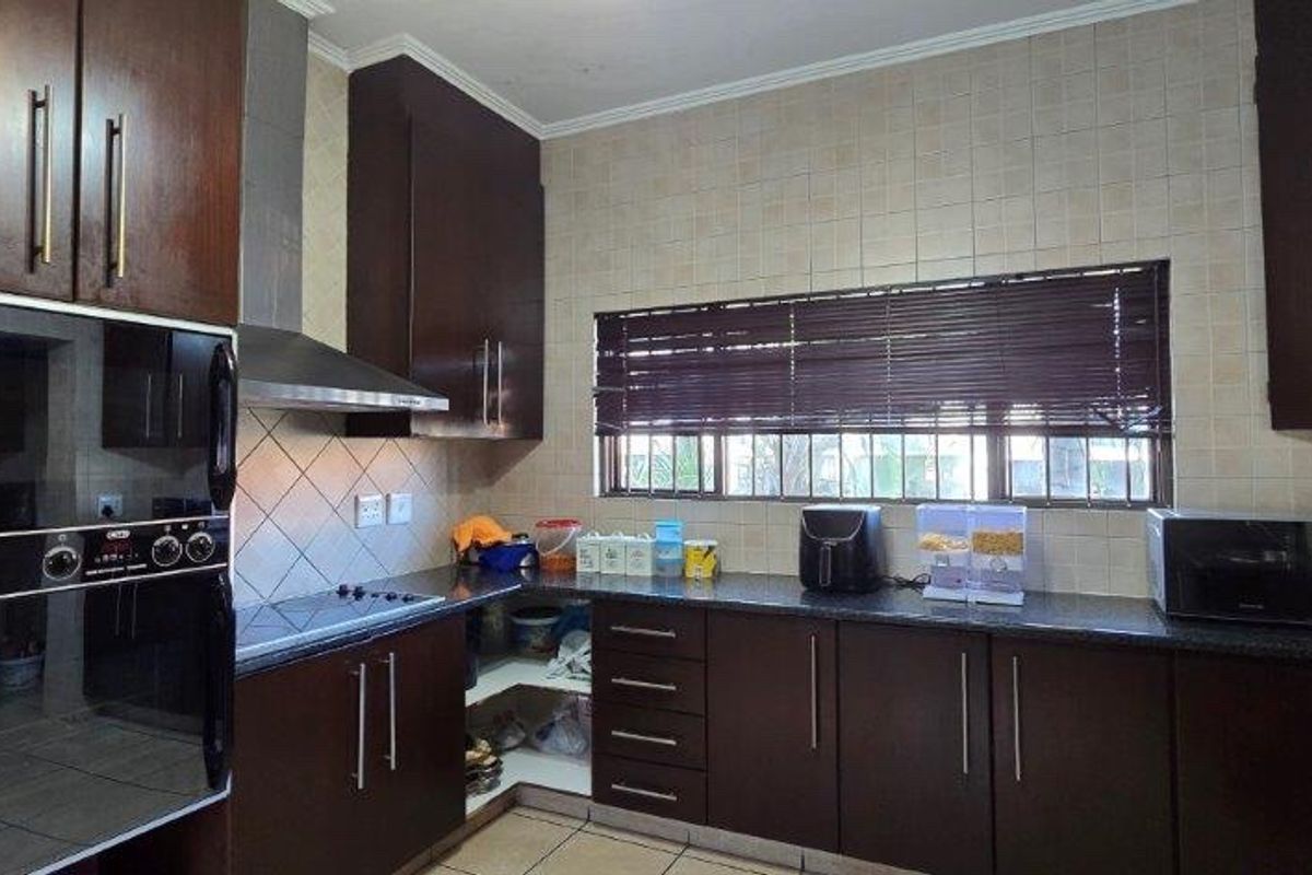 A functional kitchen featuring dark wood cabinetry, granite countertops, a built-in oven, and a tiled backsplash, offering ample storage and workspace.